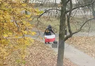 Flagi zerwane z budynków. Jedna w koszu, inna w studzience