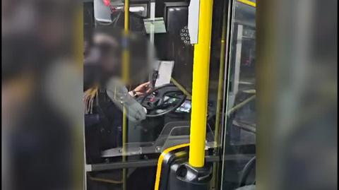 Kierowca prowadzi autobus z telefonem w ręce